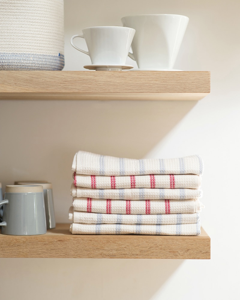 Mungo Linen and Cotton Waffle Weave Kitchen Towels in Lavender and Red Stripe, stacked on kitchen shelves with ceramic white mugs. Perfect for spring cleaning