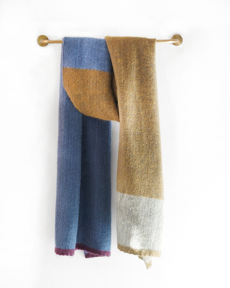 MOS Wrap in Honeybee woven with silk, bamboo, mohair, hanging over a rail.